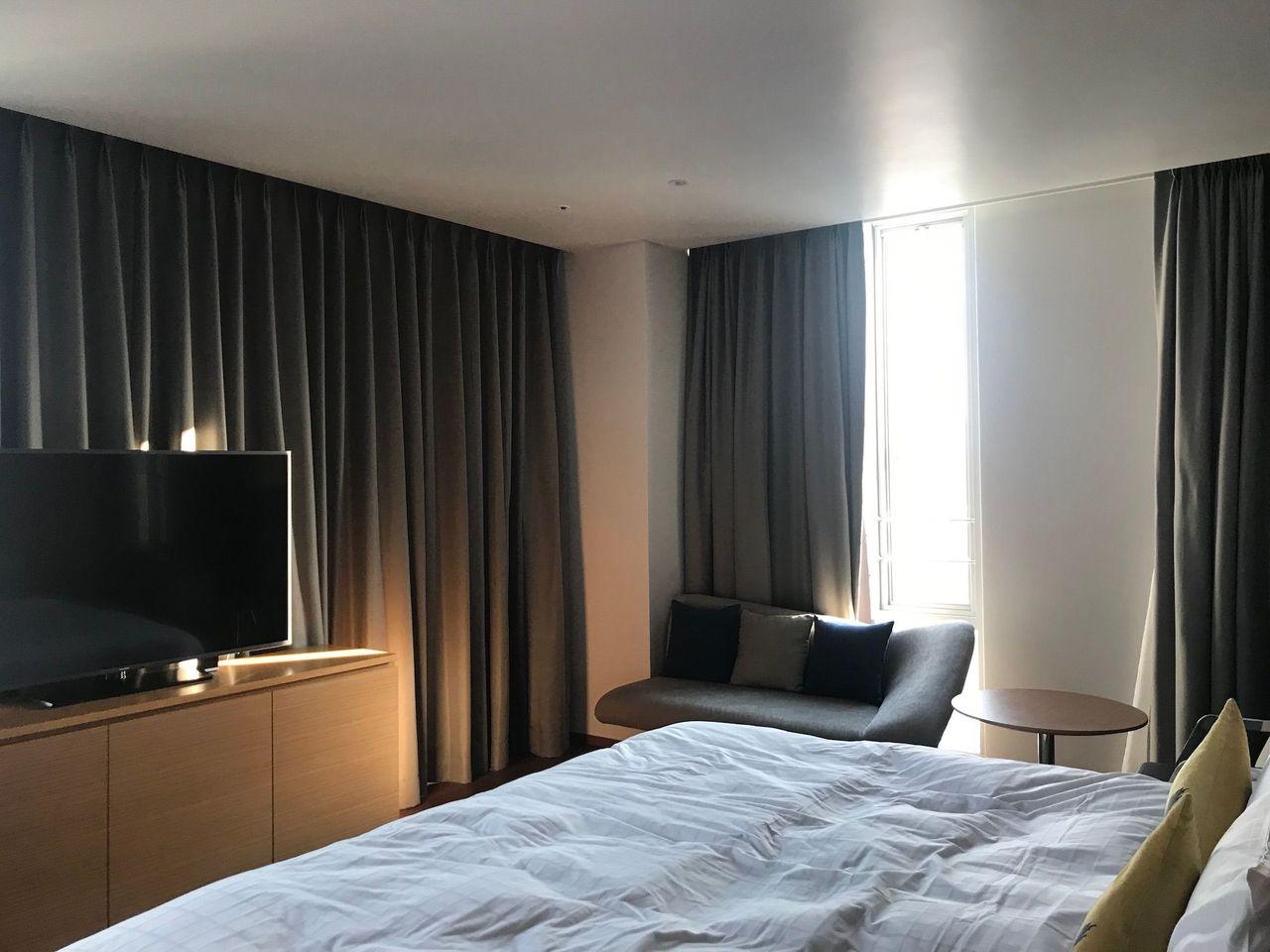 Spacious hotel room with a TV, cozy couch, and a bed at Dongdaemun Novotel Ambassador Hotel.